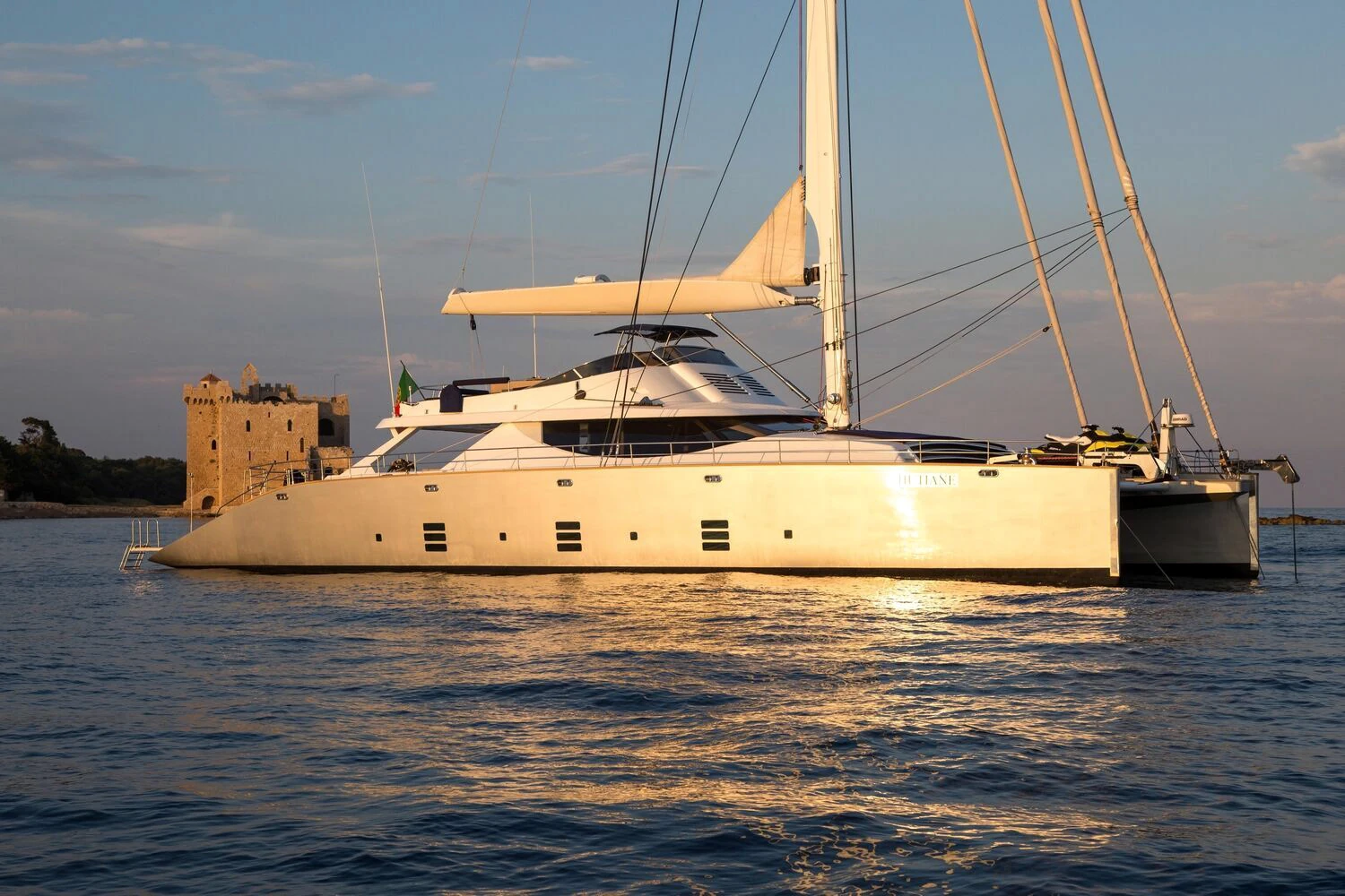 Sailing catamaran photographed at anchor in warm Mediterranean light