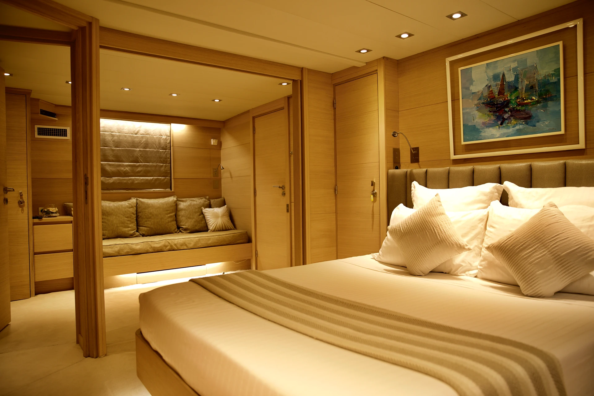 Warm timber yacht room with a large bed and integrated seating