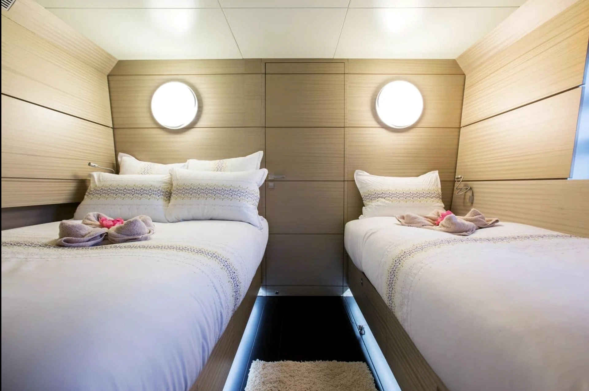 Cabine de yacht claire avec deux couchages et hublots circulaires